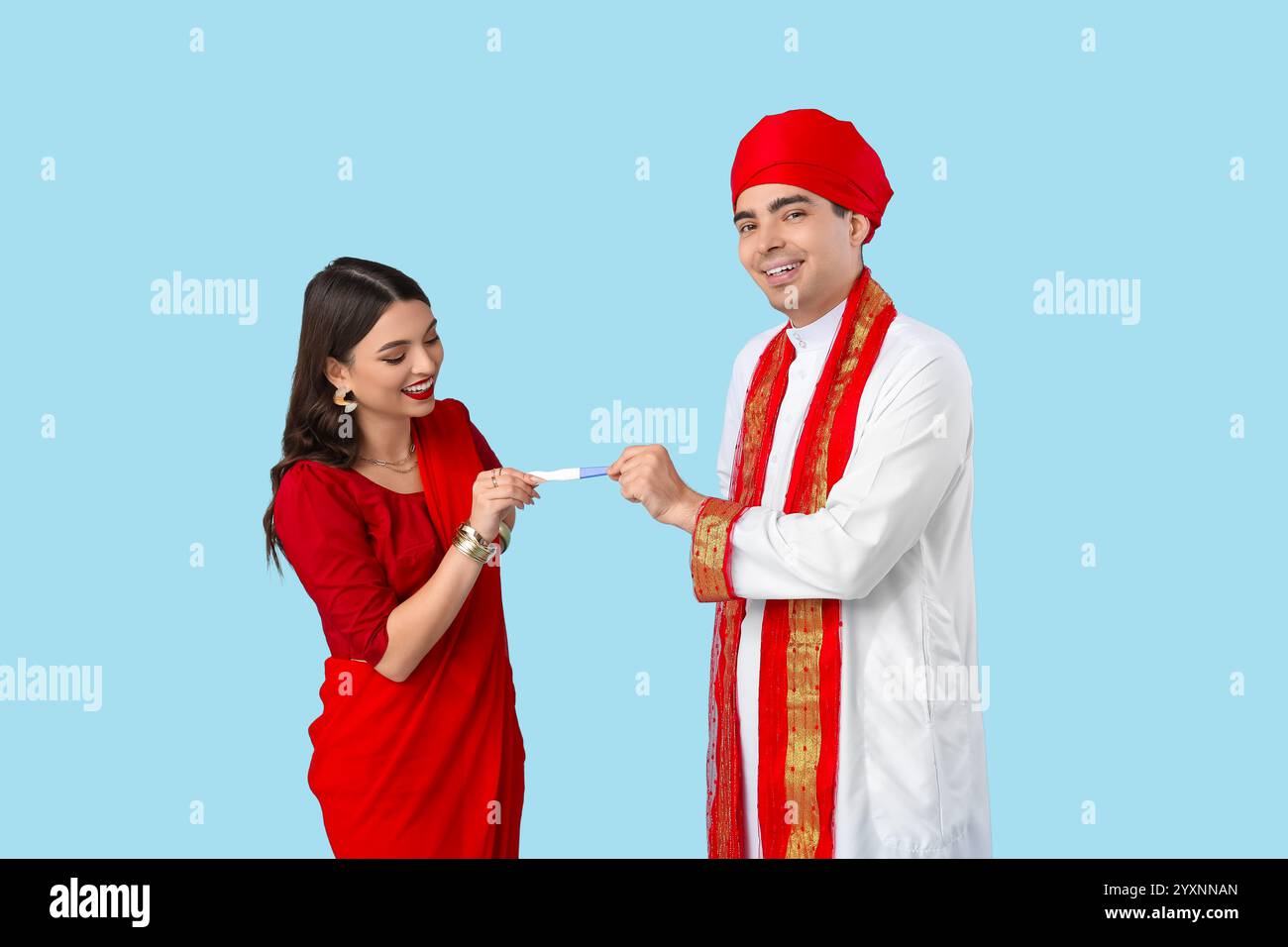 Schönes indisches Paar mit Schwangerschaftstest auf blauem Hintergrund Stockfoto