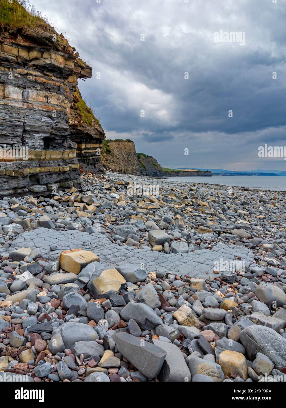 Blick auf den felsigen Strand mit stürmischem Himmel bei Kilve im Norden von Somerset England, Großbritannien, eine Site of Special Scientific Interest, die für ihre Fossilien berühmt ist. Stockfoto