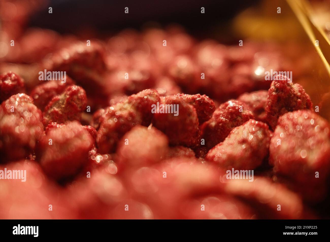 Eine Nahaufnahme von roten Nüssen mit einer glänzenden Glasur. Die Nüsse stapeln sich übereinander, wodurch ein optisch ansprechendes und appetitliches Display entsteht Stockfoto