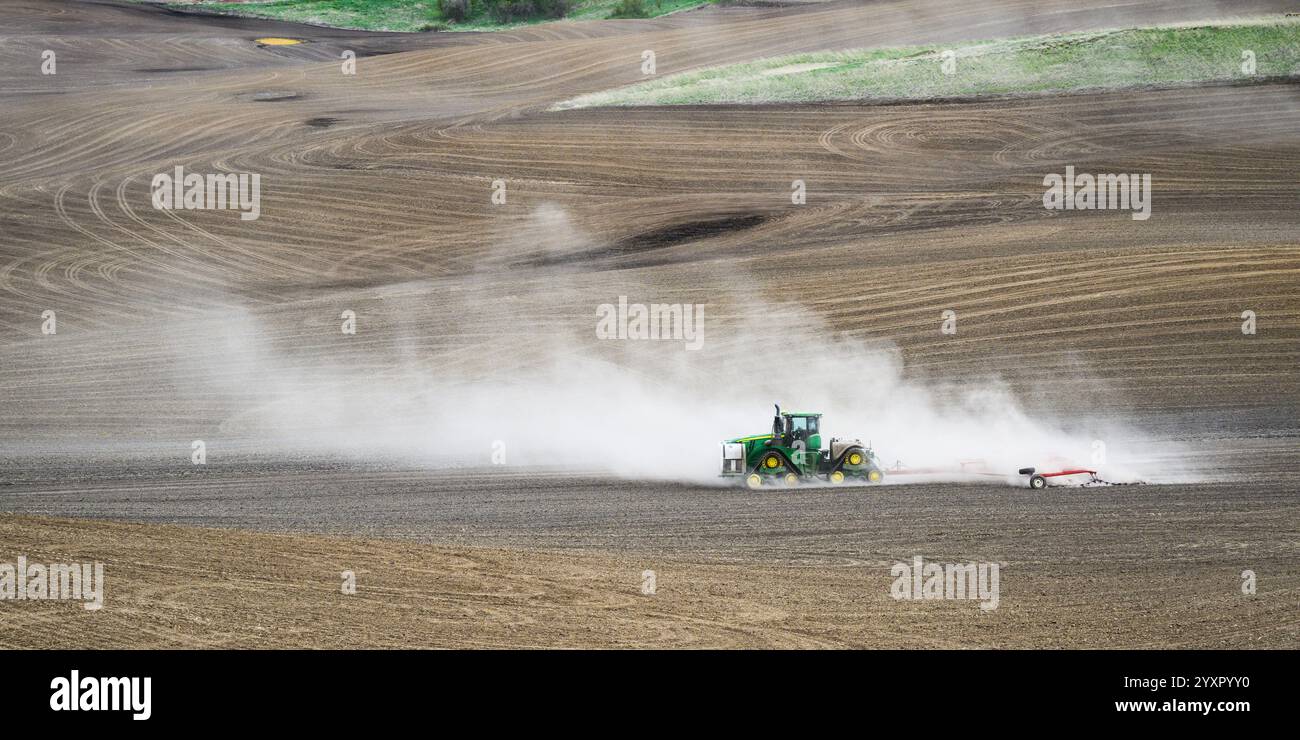 Pullman, WA, USA - 27. April 2024; knickgelenkter Kettendozer Green John Deere 9620RX überquert das Federfeld in Palouse mit Staubwolke Stockfoto