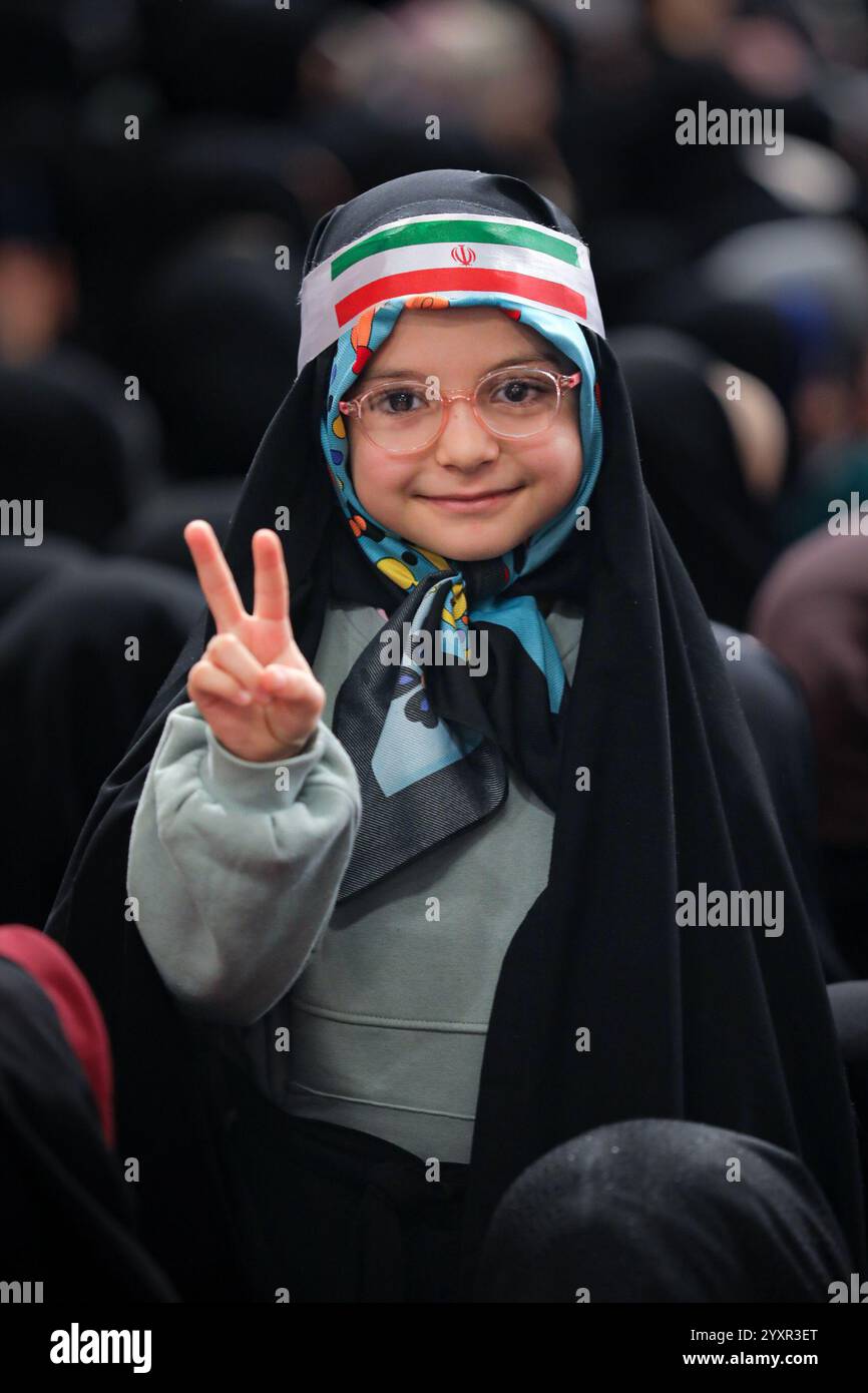 Teheran, Iran. Dezember 2024. Ein verhülltes iranisches Mädchen in einem schwarzen Tschador, das das Kopftuch der iranischen Flagge trägt, wirft während eines Treffens mit dem Obersten iranischen Führer in Teheran ein Siegeszeichen. Khamenei erklärte, dass der glaube der Vereinigten Staaten, des israelischen Regimes und ihrer Verbündeten, dass der Widerstand beendet sei, völlig falsch sei. (Foto: © Iranian Supreme Leader's Office via ZUMA Press Wire) NUR REDAKTIONELLE VERWENDUNG! Nicht für kommerzielle ZWECKE! Stockfoto