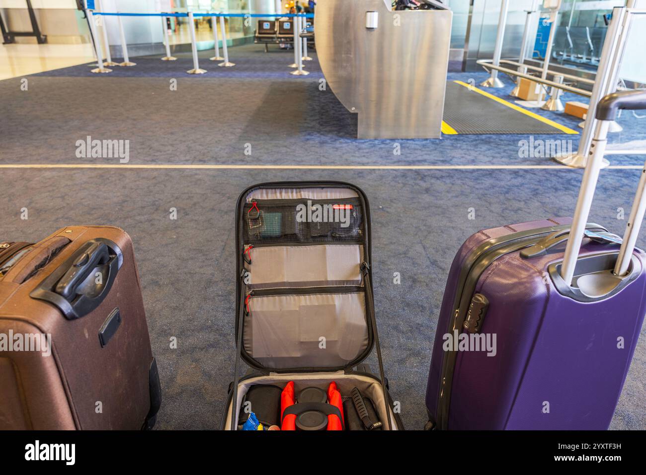 Öffnen Sie den Koffer mit Reisefotoausrüstung und zwei Taschen auf der Etage des Flughafenterminals mit Teppichboden in der Nähe des Check-in-Schalters. Miami. USA. Stockfoto