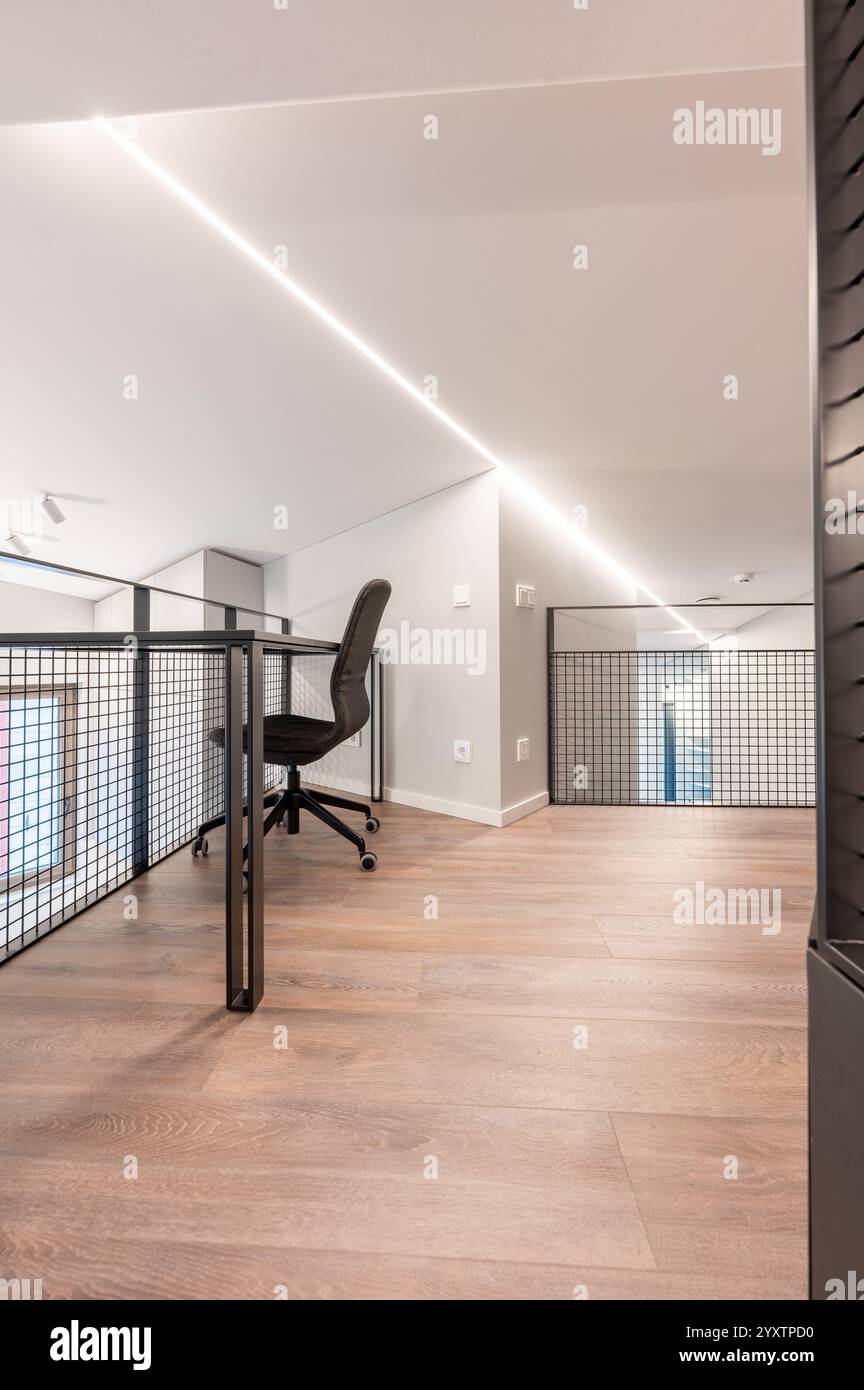 Stilvolles Büro-Loft mit modernem ergonomischem Stuhl, großem Holzboden und schlanken minimalistischen Designelementen, perfekt für kreative Profis Stockfoto