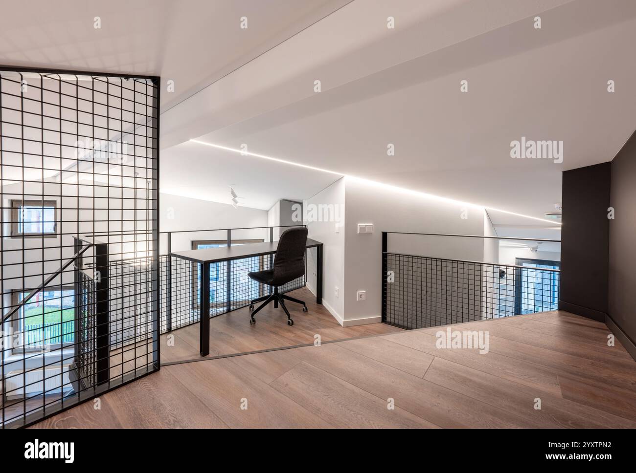 Stilvolles Büro-Loft mit modernem ergonomischem Stuhl, großem Holzboden und schlanken minimalistischen Designelementen, perfekt für kreative Profis Stockfoto
