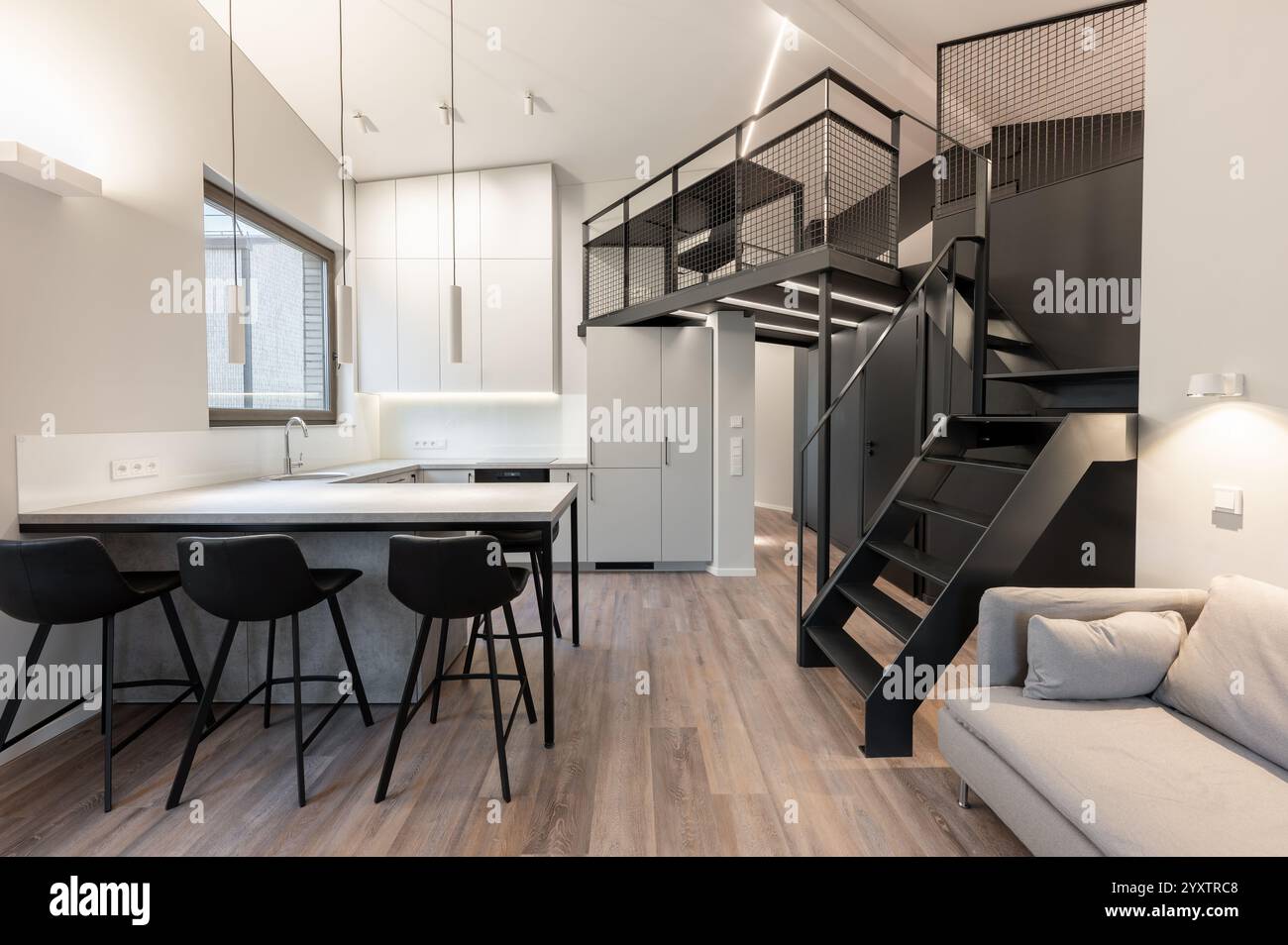 Ein elegantes und modernes Loft-Apartment mit offener Küche mit Barhockern, Arbeitsbereich im Zwischengeschoss und klarem minimalistischem Design. Modern Stockfoto