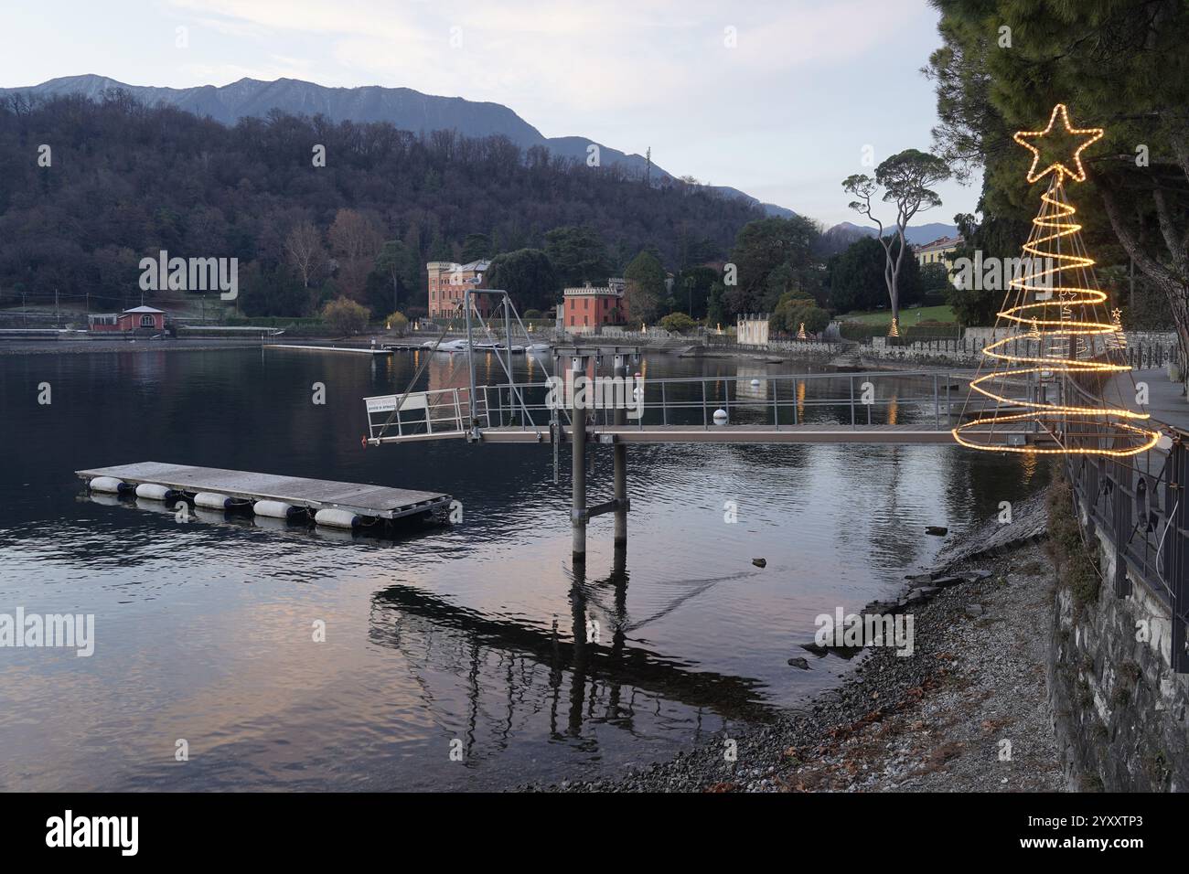 Am See von Lenno mit Weihnachtsdekorationen bei Sonnenaufgang, im Hintergrund Bellagio und seine Landzunge. Comer See, Italien Stockfoto