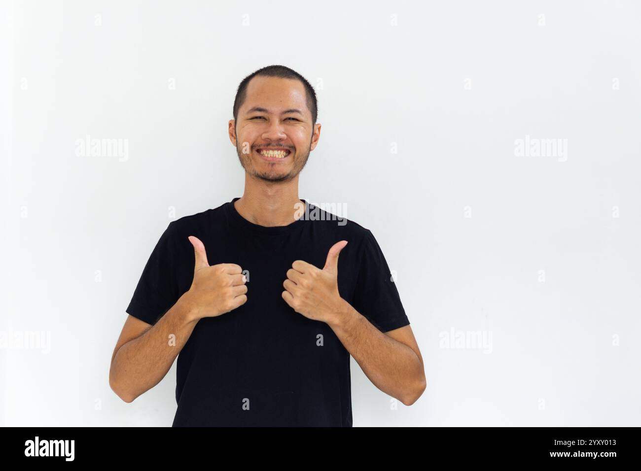 Junge asiatische Männer mit schwarzem Hemd geben die Daumen mit glücklichem Ausdruck auf isoliertem weißem Hintergrund Stockfoto