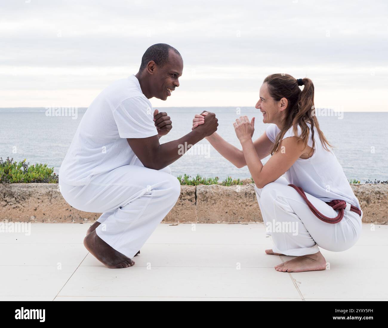 Zwei Personen üben Capoeira im Freien mit malerischem Meerblick Stockfoto