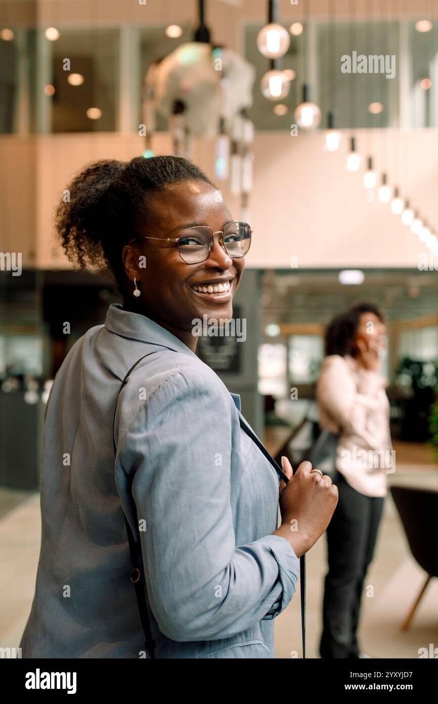 Porträt einer lächelnden Geschäftsfrau, die im Kongresszentrum über die Schulter schaut Stockfoto