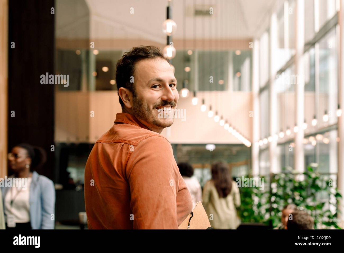 Porträt eines lächelnden männlichen Geschäftsmannes, der im Kongresszentrum über die Schulter schaut Stockfoto