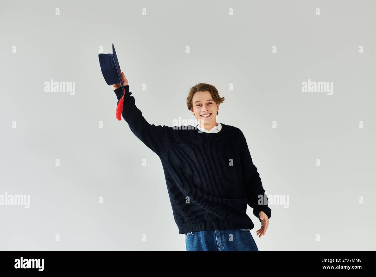 Ein junger Mann in einer Abschlussmütze feiert seine akademische Leistung. Stockfoto