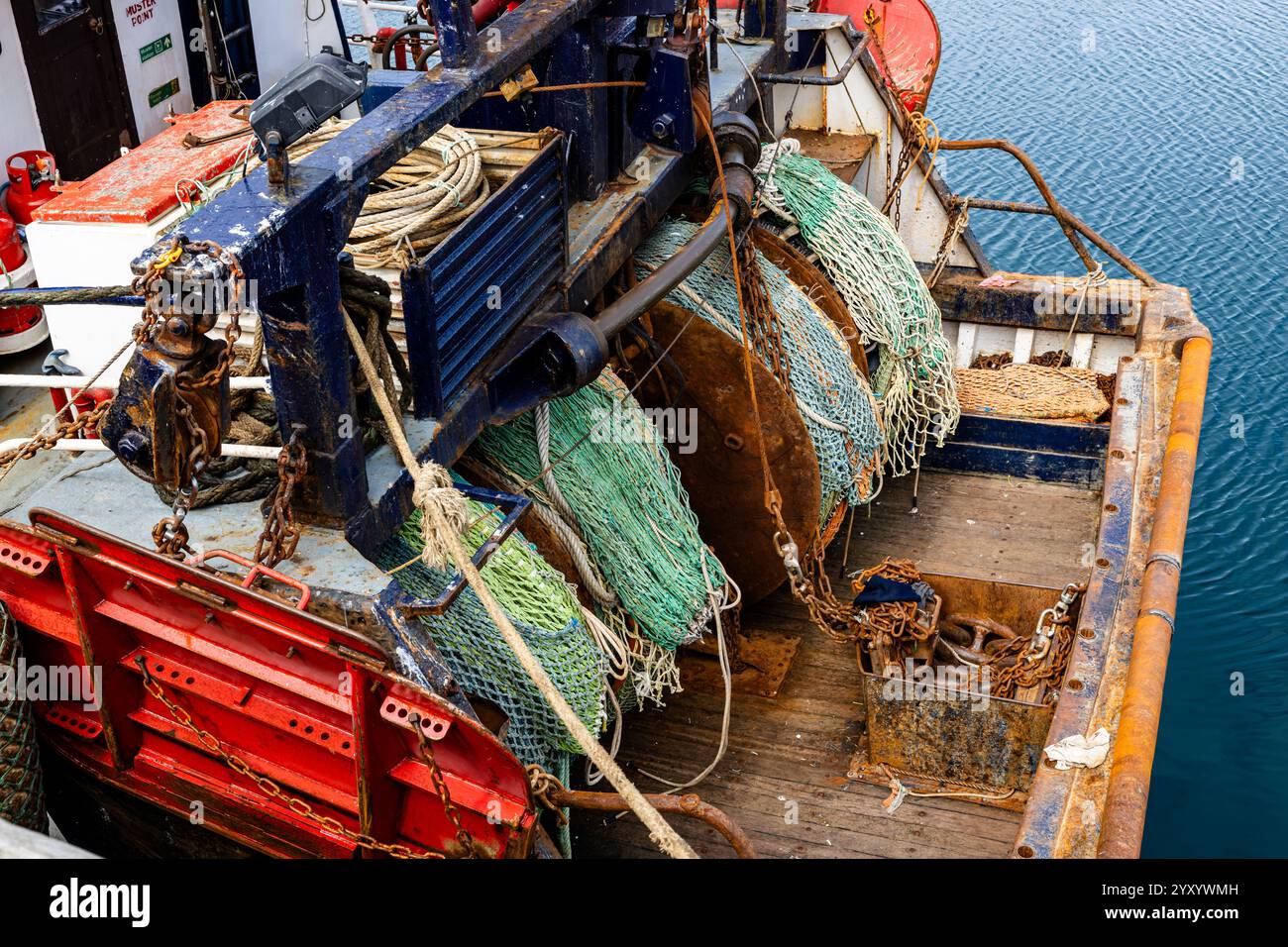 stern-Ende eines Fischtrawlers mit den Netzen, die an einer Hafenmauer befestigt sind Stockfoto