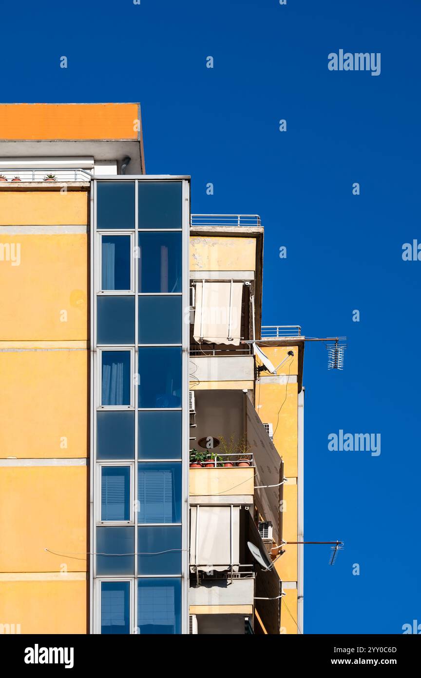 Detail eines gelben Apartmentblocks mit Balkonen in Tirana, Albanien, 7. Dezember 2024 Stockfoto