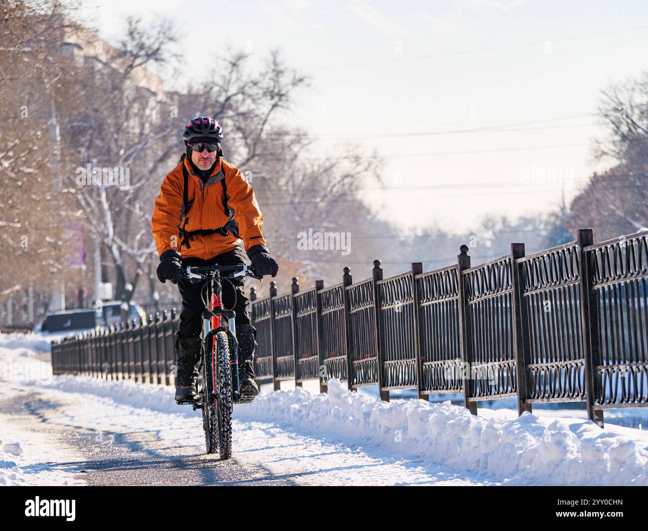 Ein aufregendes Winterabenteuer in der Stadt mit dem Fahrrad. Ein Mann fährt Fahrrad auf einer verschneiten Straße Stockfoto