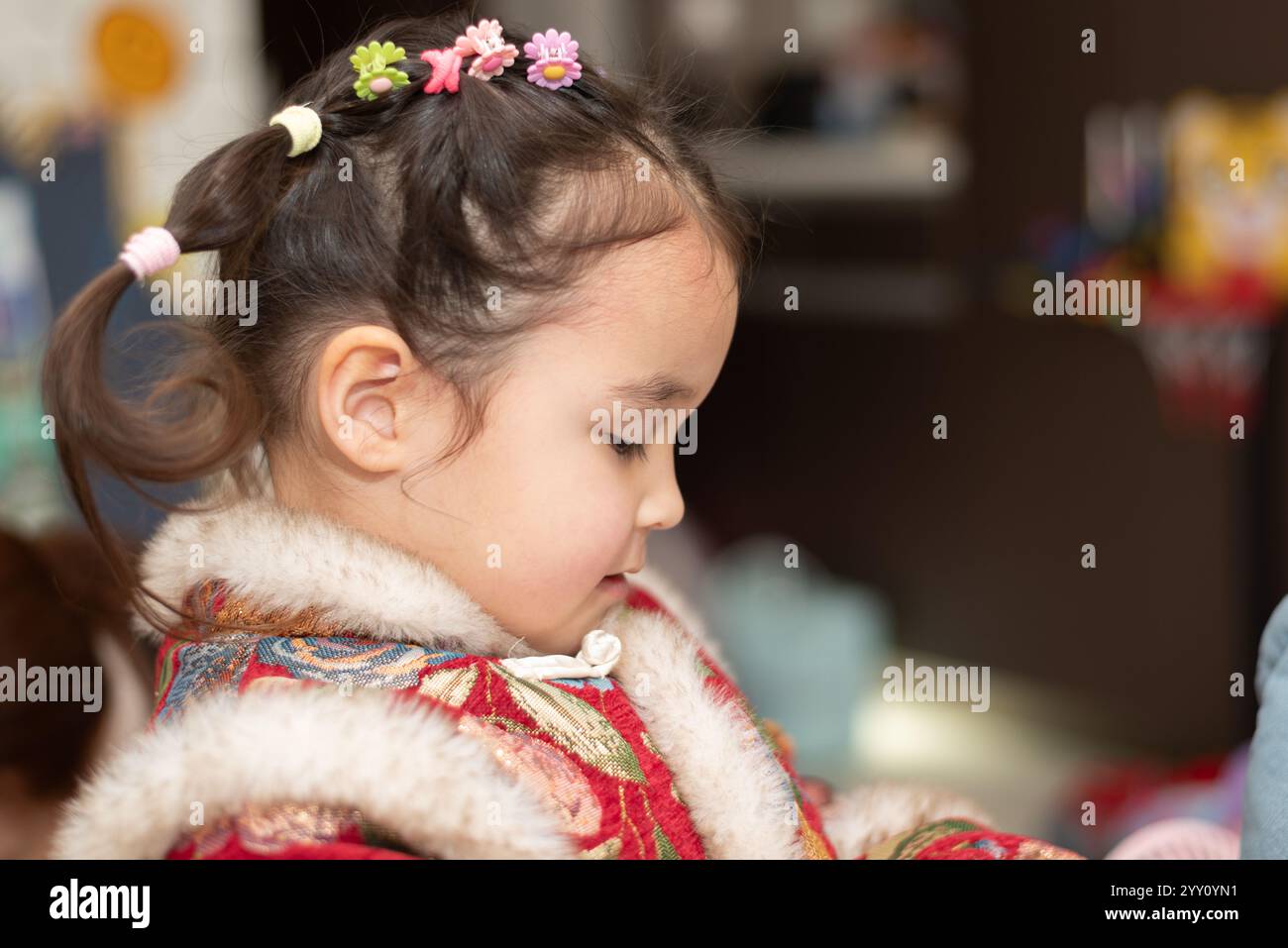 Nahaufnahme Porträt eines süßen kleinen multirassischen Mädchens in traditioneller chinesischer Kleidung, bereit für das chinesische Neujahrsfest. Sie posiert für ein Foto Stockfoto