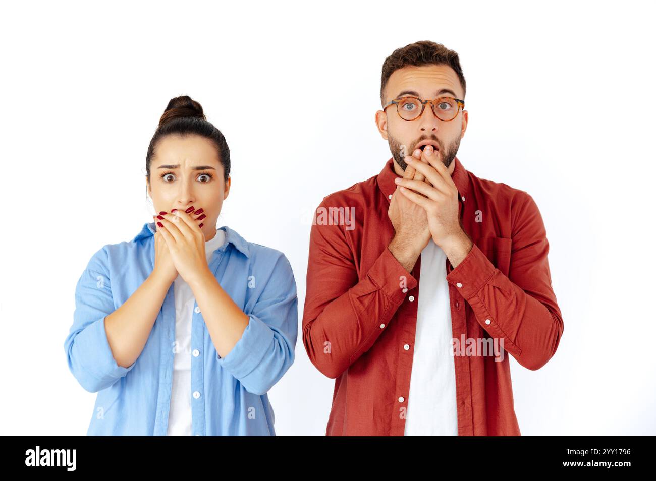 Schockierte Männer und Frauen, die ihren Mund mit Händen bedecken, überrascht oder ungläubig zeigen, in lässiger Kleidung gekleidet, stehen auf isoliertem weißen Hintergrund und schauen in die Kamera Stockfoto