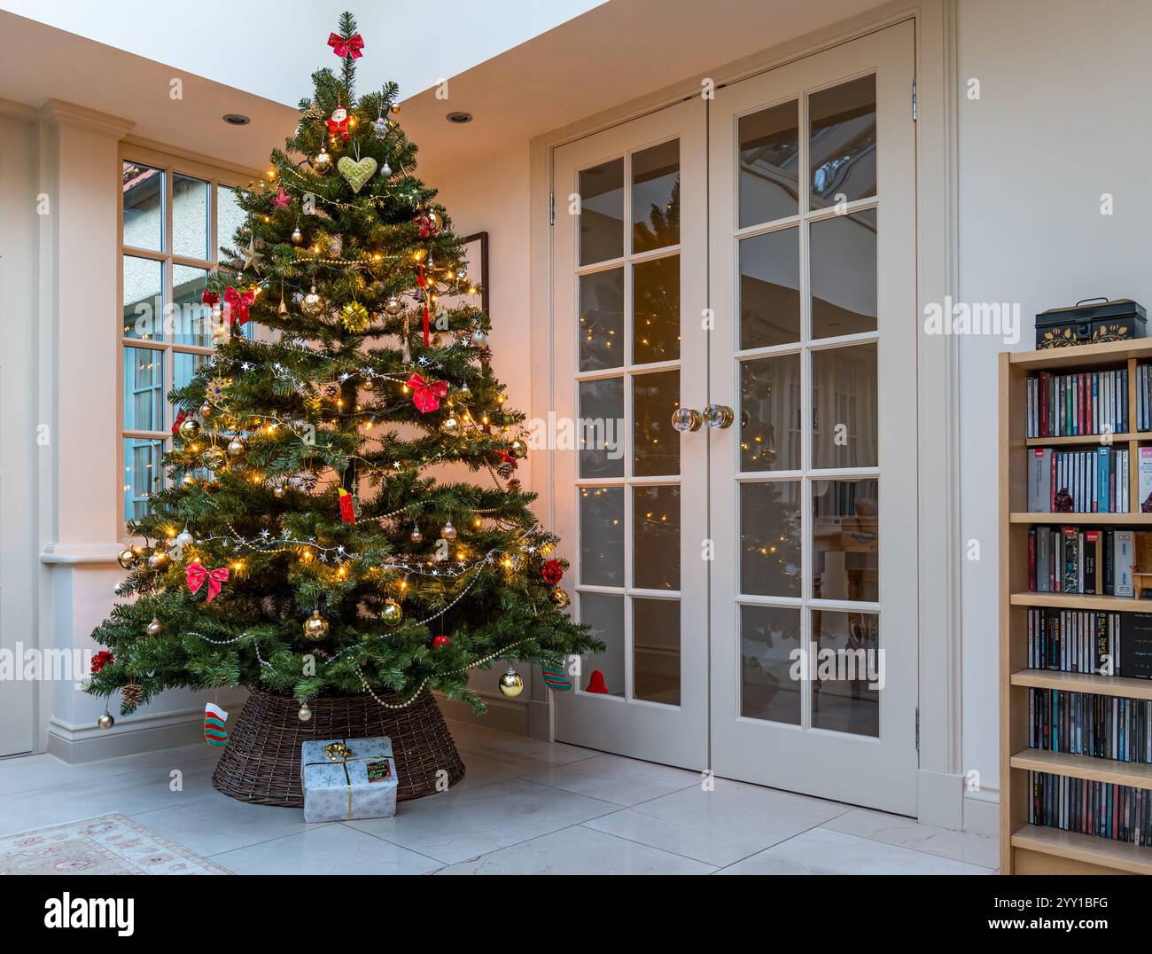 Inneneinrichtung mit geschmücktem Weihnachtsbaum und Geschenk unter dem Baum im Wohnzimmer Wintergarten, Großbritannien Stockfoto