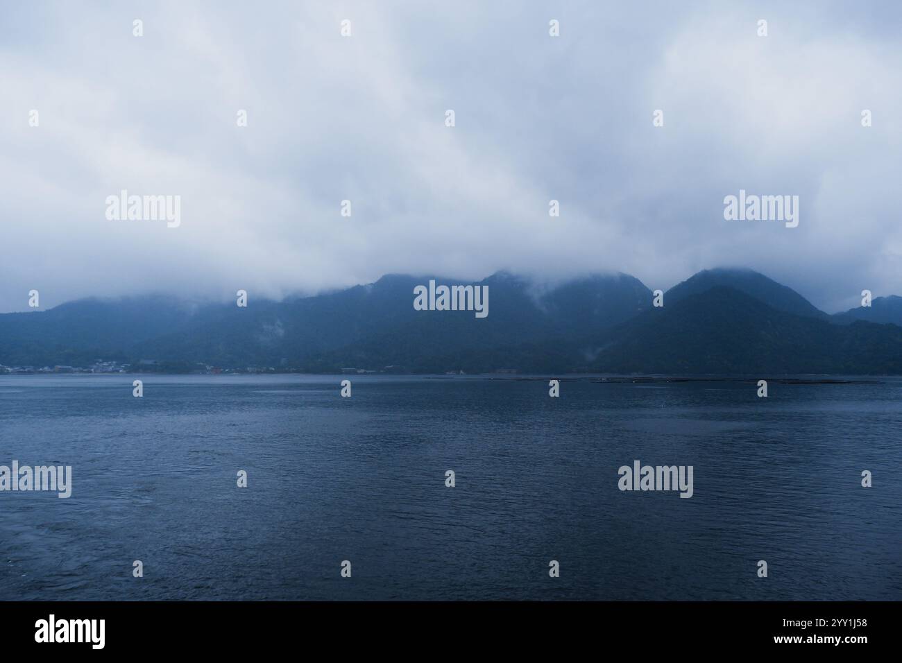 Atemberaubende japanische Natur mit Grün, Nebelbergen, Wasser, Wolken und einem traditionellen Torii-Tor, wunderschöne ruhige Landschaft Stockfoto