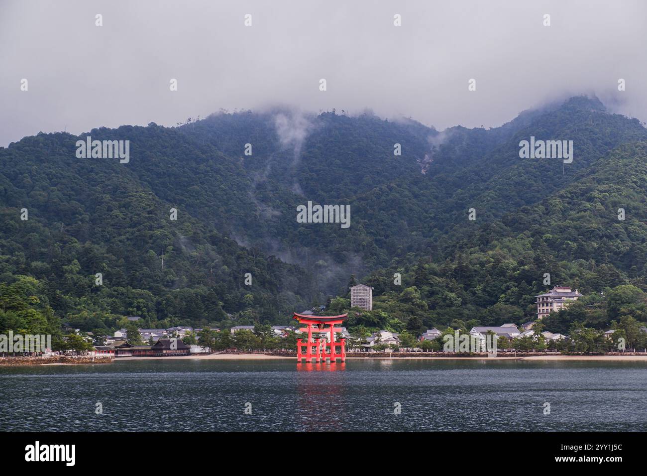 Atemberaubende japanische Natur mit Grün, Nebelbergen, Wasser, Wolken und einem traditionellen Torii-Tor, wunderschöne ruhige Landschaft Stockfoto