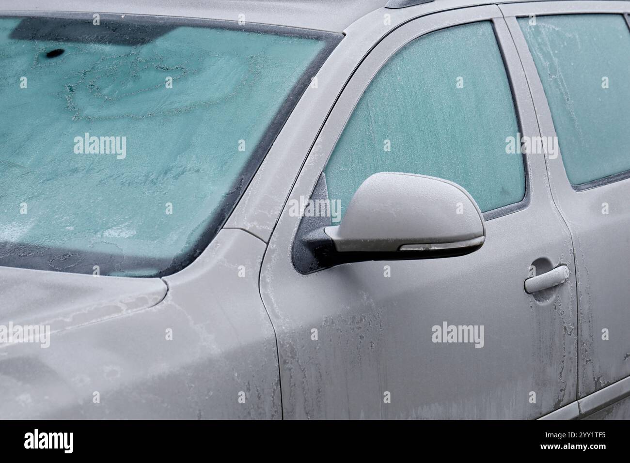 Gefrorene Fenster eines Autos an einem kalten Wintertag, Nahaufnahme eines grauen Autos mit Eiskristallen Stockfoto