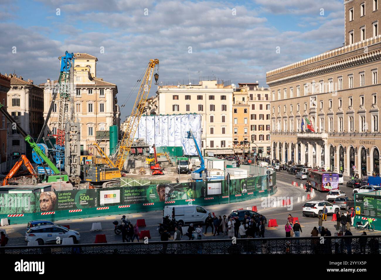 Rom, Italien. Dezember 2024. Kräne und LKWs rund um die „Konstellationen von Rom“, den Titel der monumentalen Intervention, die Pietro Ruffo auf den zehn Silos unterzeichnet hat, die die Baustelle der Metro C auf der Piazza Venezia begrenzen. Das erste Werk eines Zyklus wurde vorgestellt, der sich in den kommenden Monaten auf dieser neuen Oberfläche abwechseln wird, die der zeitgenössischen Kunst verliehen wird. Mit „Murales“, dem Titel des Projekts, das von Webuild, einem Unternehmen, das am Bau der C-Linie der U-Bahn in Rom arbeitet, gefördert wurde, verwandelt sich die Baustelle in eine Gelegenheit zur Stadterneuerung. (Bild: © Stefano Co Stockfoto