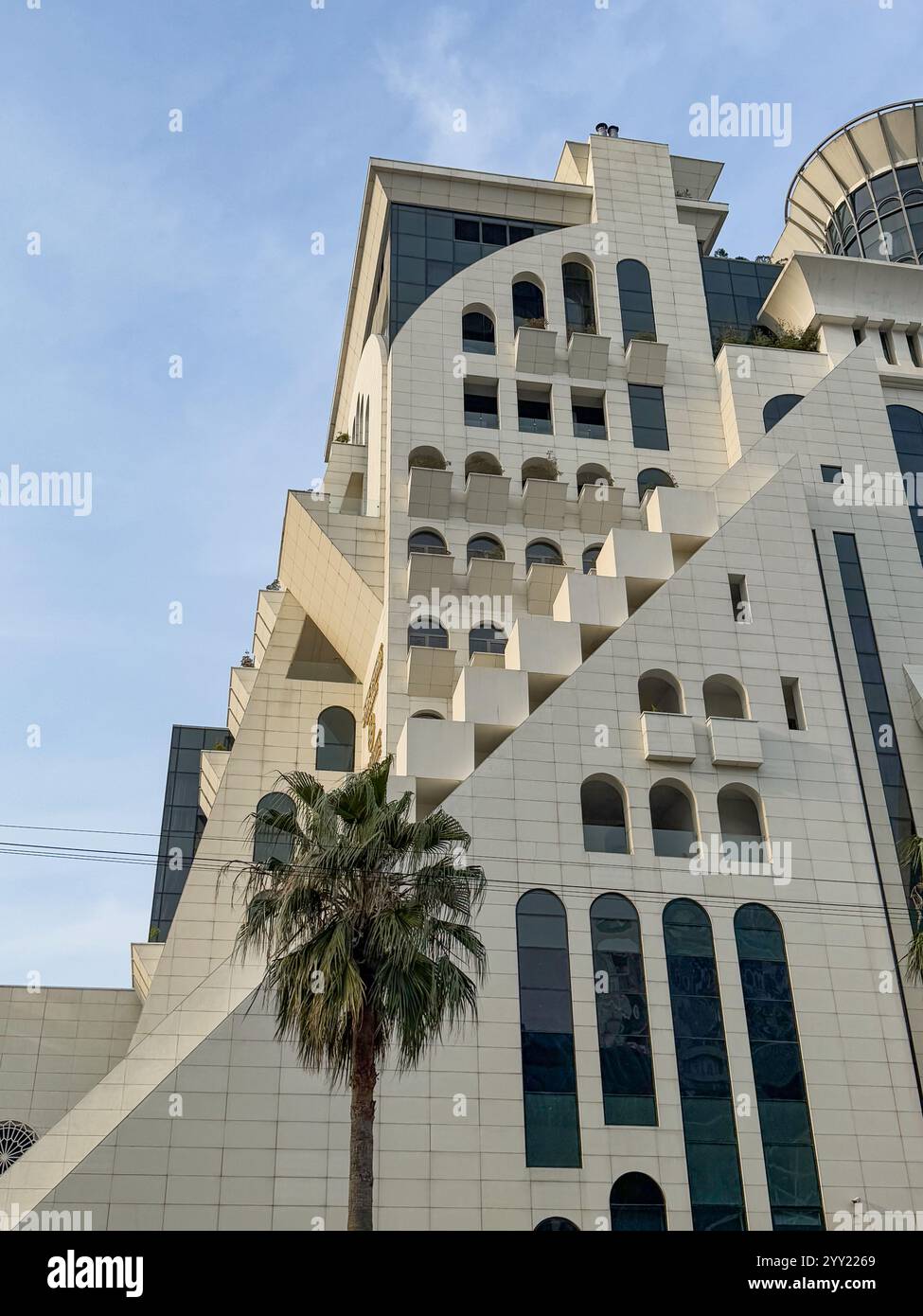 Dieses Foto zeigt eine moderne architektonische Struktur mit auffälligen geometrischen Designs und sauberen weißen Oberflächen. Das Gebäude weist einen scharfen Winkel auf Stockfoto