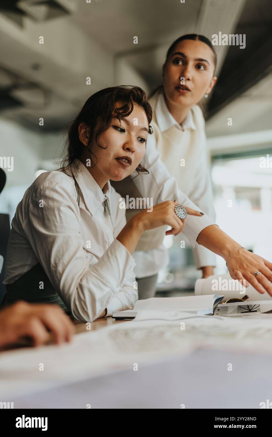 Zwei verschiedene Geschäftsfrauen nehmen an einem Brainstorming Teil, analysieren Dokumente und diskutieren Ideen für ein neues Projekt. Stockfoto