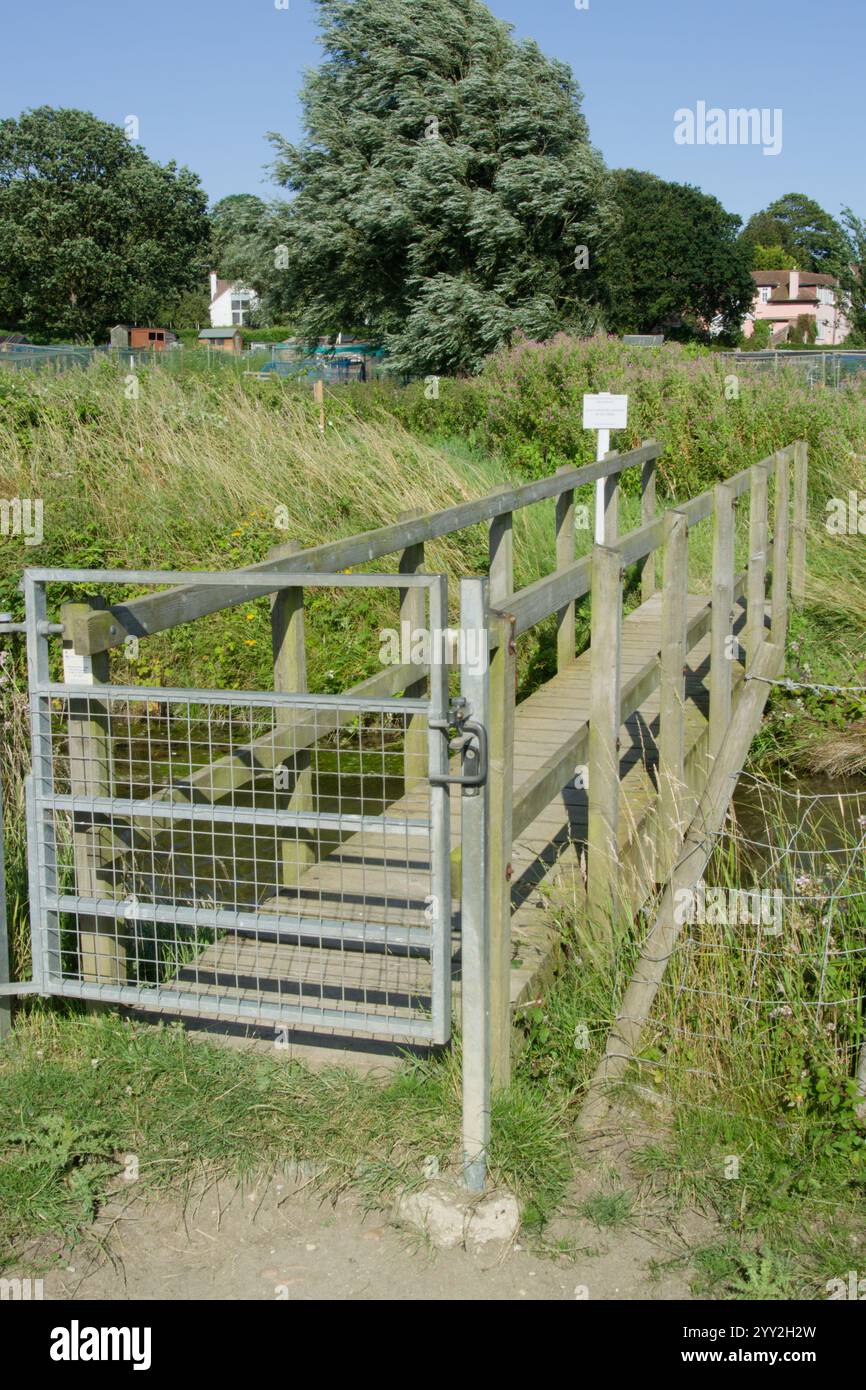 Holzsteg mit Metalltor an einem Ende auf dem Fußweg in der Nähe von Aldeburgh, Suffolk, Großbritannien Stockfoto