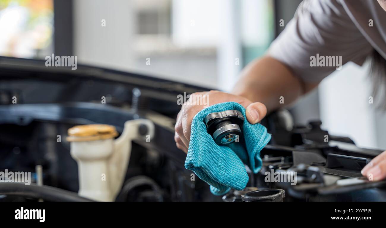 Eine Frau nimmt die Sache mit dem Nachfüllen des Heizkörpers. Mechaniker, der Automotorreparaturen in einer Autowerkstatt durchführt. Eine Nahaufnahme einer Hand, die Wasser t hinzufügt Stockfoto