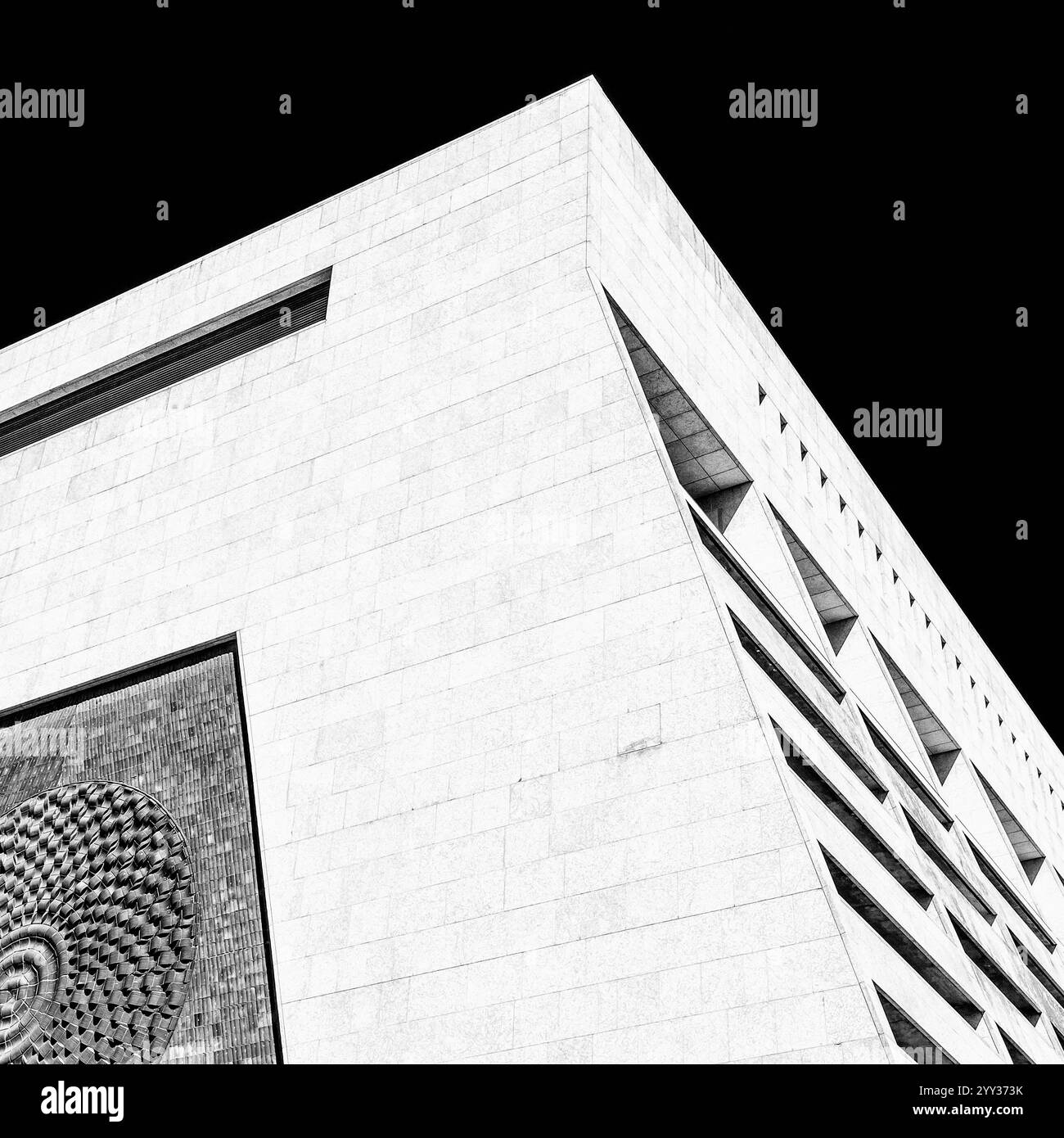 Ein hohes, weißes Gebäude mit einem großen Fenster an der Seite. Das Gebäude hat ein modernes Design und ist ein Geschäfts- oder Bürogebäude Stockfoto