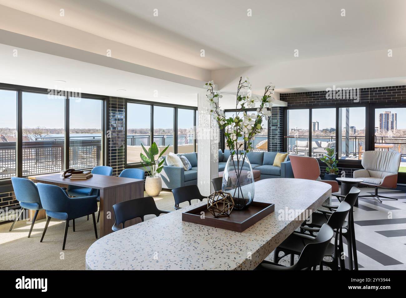 Ein Gemeinschaftsraum im obersten Stockwerk eines Appartementgebäudes mit vielen Fenstern, die auf die Außenterrasse blicken Stockfoto