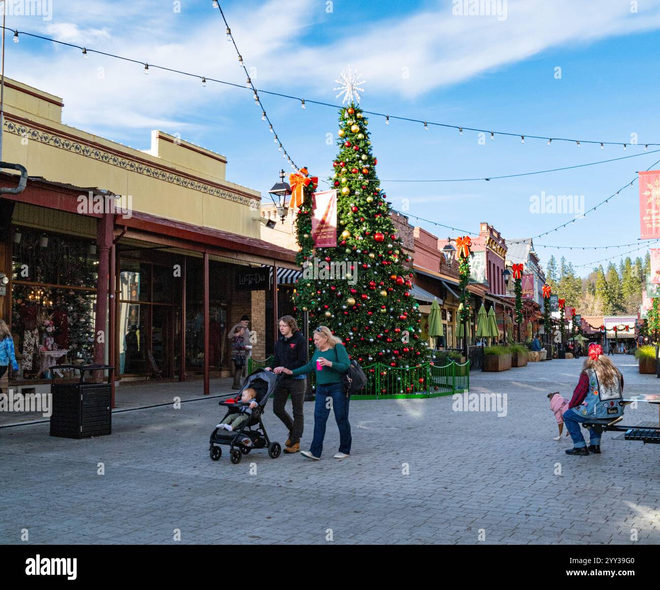 Eine Familie spaziert vorbei an dem geschmückten Weihnachtsbaum in der Mill Street, einer Fußgängerzone im historischen Stadtzentrum dieser Stadt in den Ausläufern der Sierra. Stockfoto