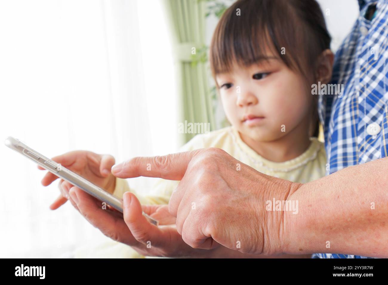 Kind, das ein Telefon mit Oma benutzt Stockfoto