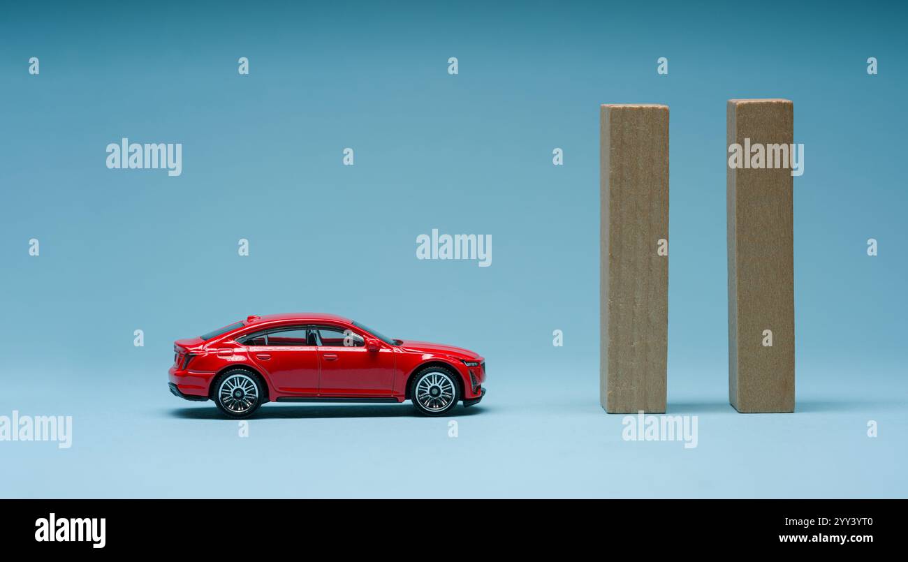 Holzblöcke vor dem roten Spielzeugauto auf blauem Hintergrund. Problem, Frustrationskonzept Stockfoto