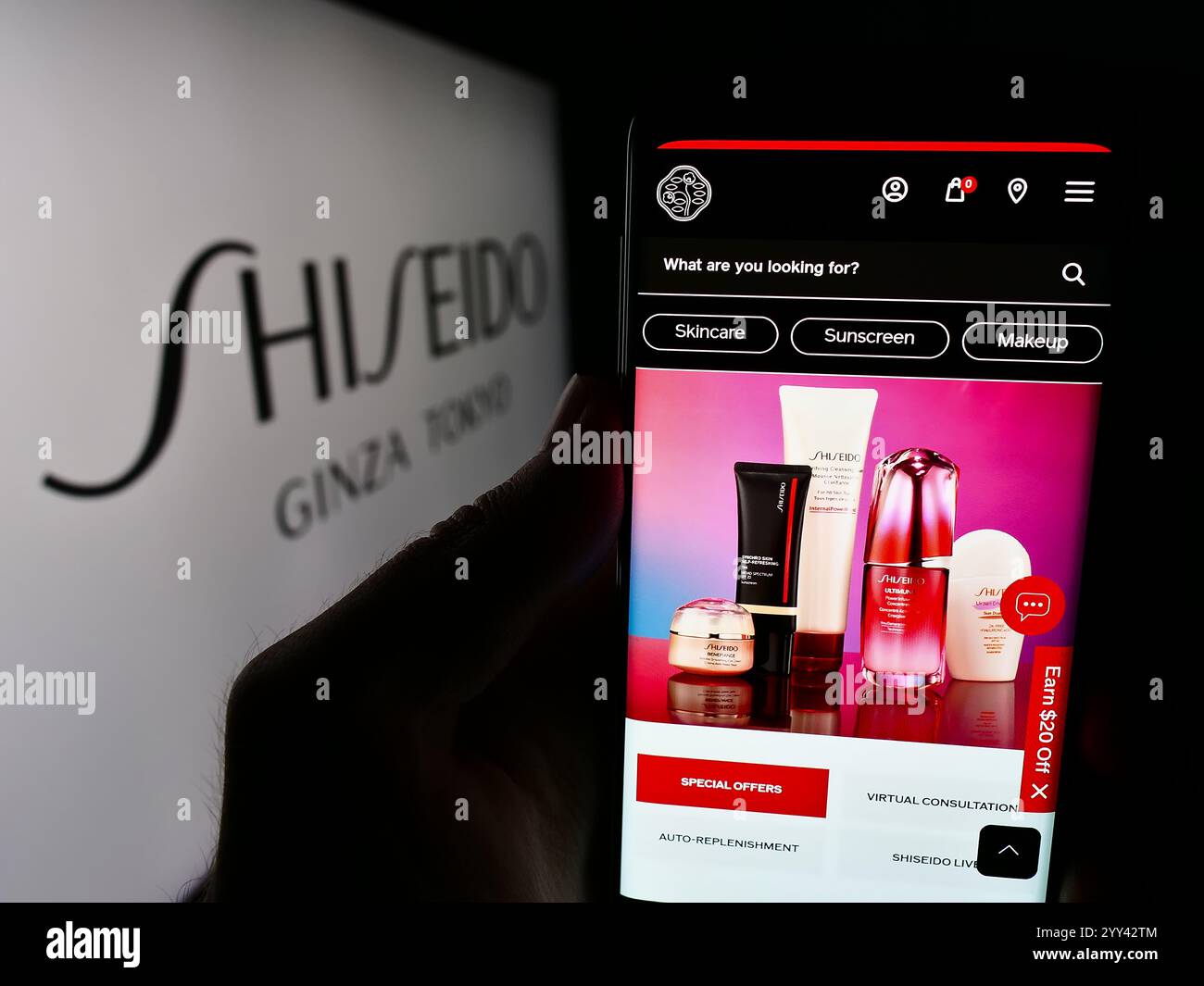 In dieser Abbildung hält eine Person ein Smartphone mit der Website des japanischen Kosmetikunternehmens Shiseido Co. Ltd. Vor dem Logo. Stockfoto