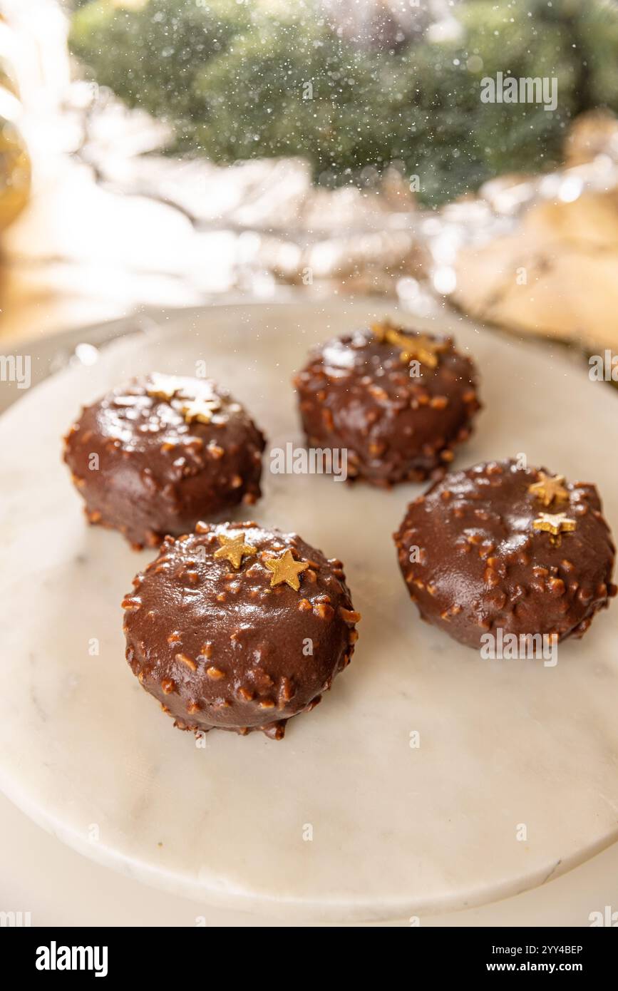 Vier mit Nüssen bedeckte und mit goldenen Sternen verzierte Schokoladenkuchen werden mit Puderzucker bestreut Stockfoto