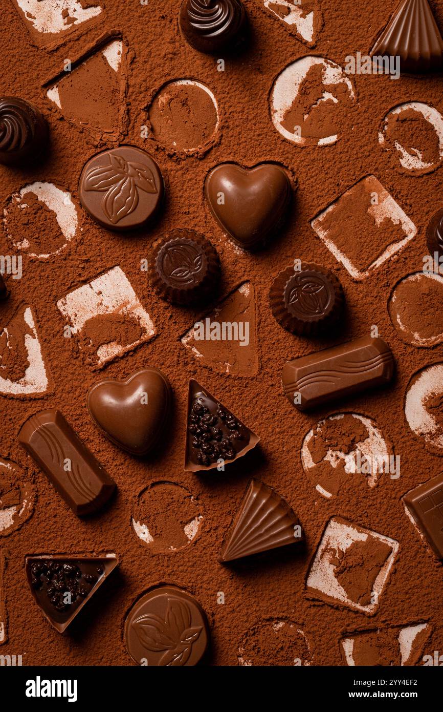 Blick von oben auf verschiedene Schokoladentrüffel, die künstlerisch auf einer Kakaopulver-staubten Oberfläche verstreut sind und das Wesen des köstlichen, süßen Desserts einfangen Stockfoto