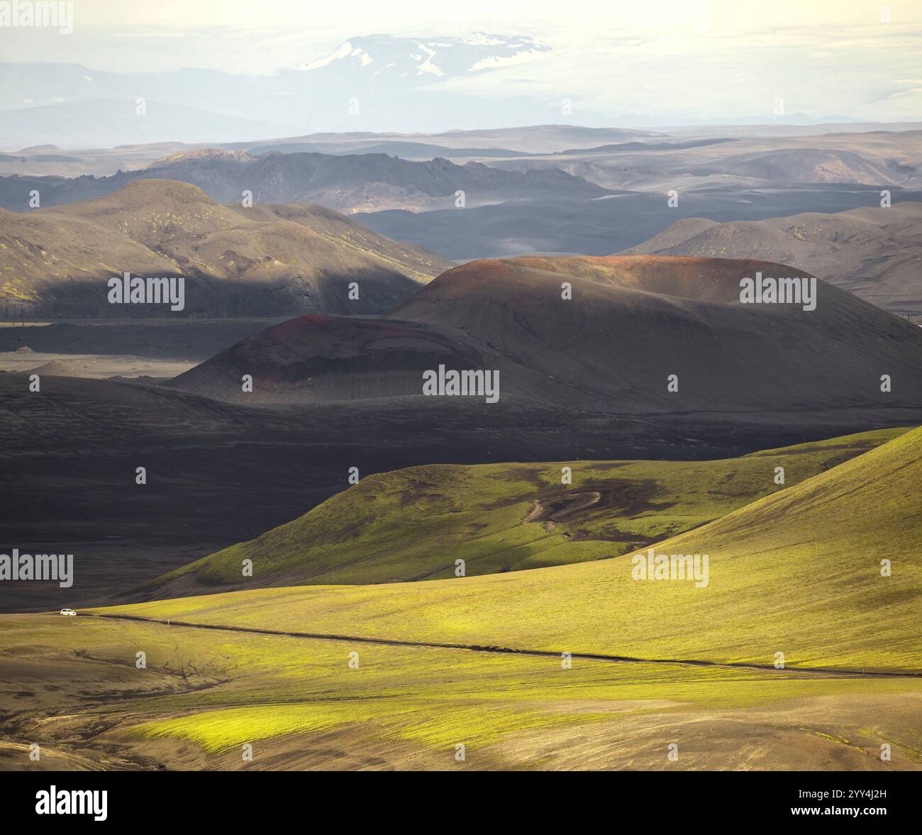 Die faszinierende isländische Hochlandlandschaft bietet üppige grüne Felder und dramatische vulkanische Formationen unter weichem, diffusem Licht, Eine ruhige, unberührte nat Stockfoto