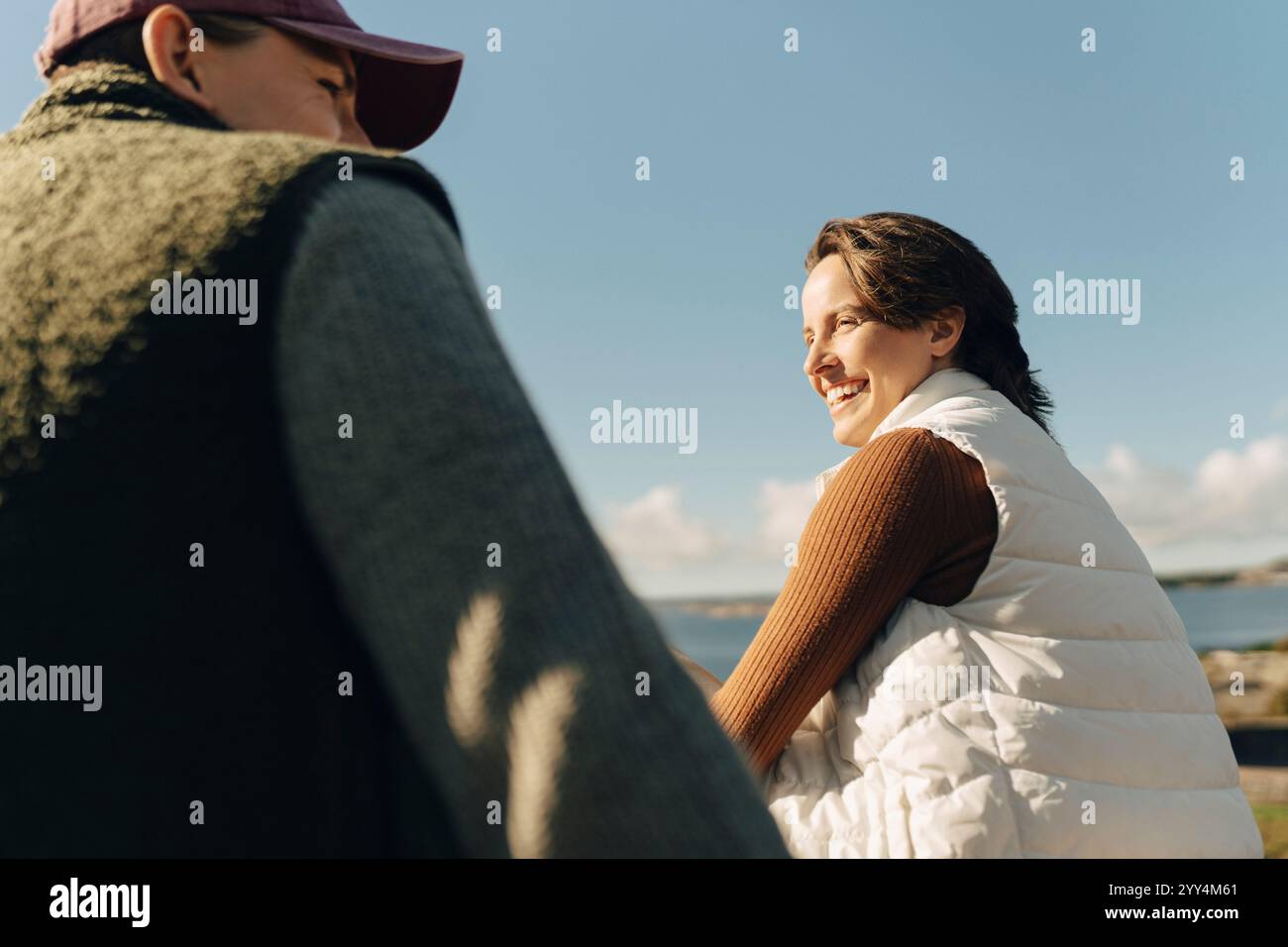 Niedrigwinkelansicht einer glücklichen kurzhaarigen Frau, die mit einem männlichen Freund am sonnigen Tag spricht Stockfoto