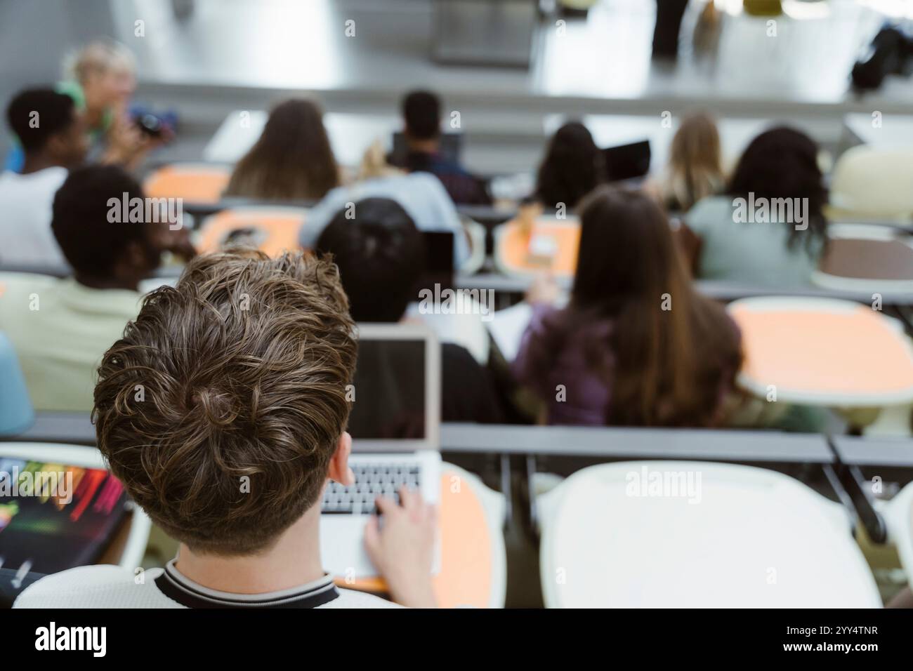 Hochwinkelansicht eines männlichen Studenten, der mit Laptop im Hörsaal der Universität sitzt Stockfoto