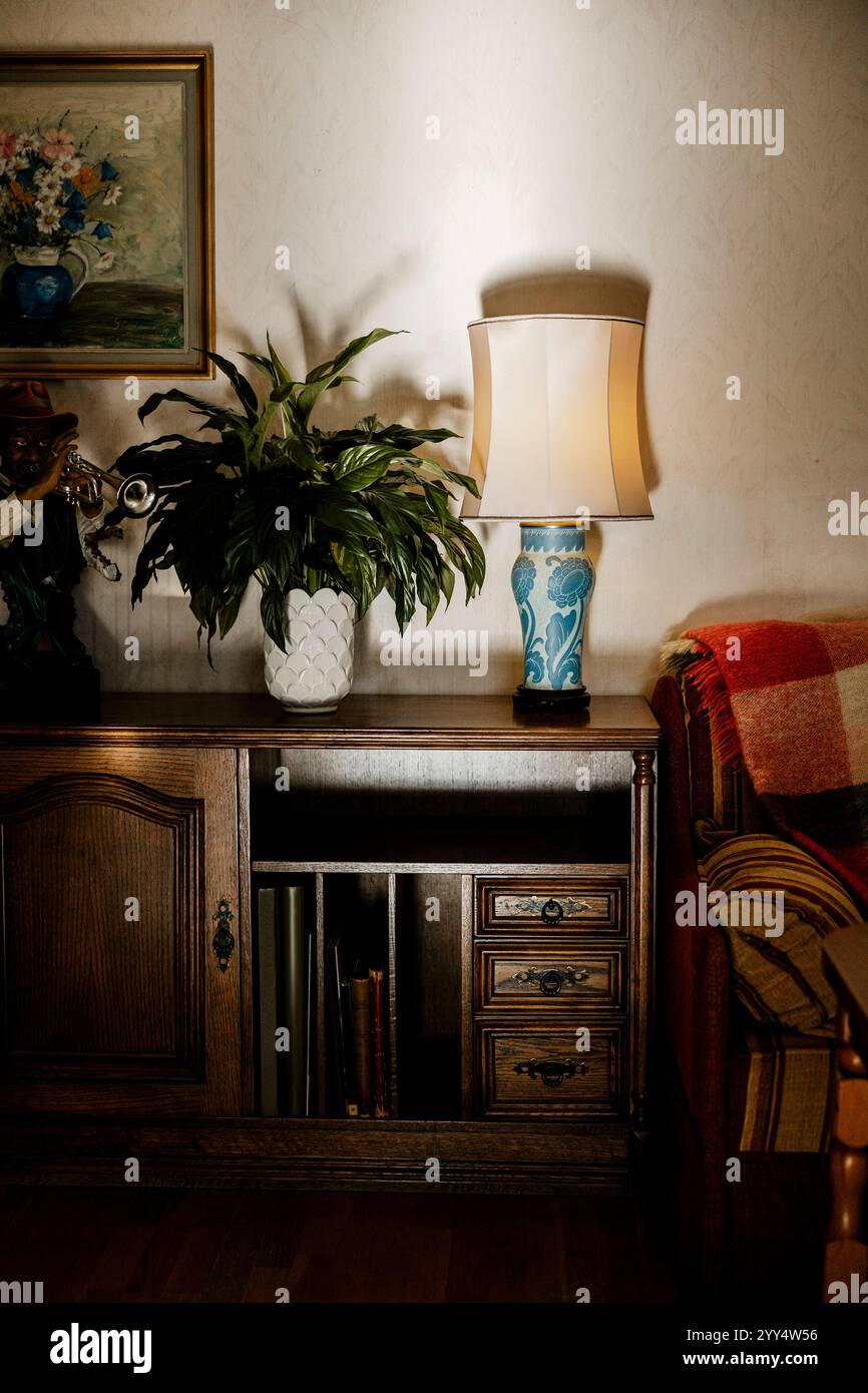 Elektrische Lampe mit Topfpflanze auf Tisch in der Nähe der Wand zu Hause Stockfoto