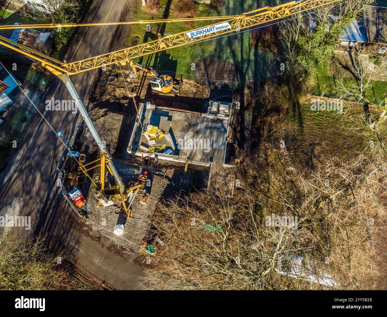 Ein Baukran steht an einer Baustelle für den Bau eines Einfamilienhauses in einer Siedlung am Waldrand. Leutkirch, Baden-Württemberg, Deutschland ein Baukran in einer Wohnsiedlung Stockfoto