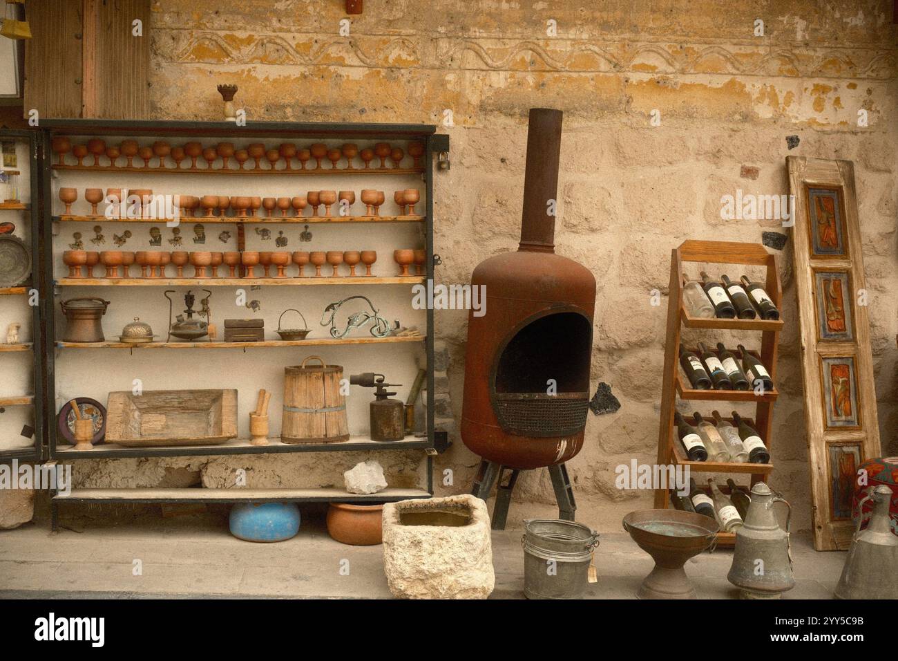 Goreme, Kappadokien, Türkiye : rustikale Ausstellung von Vintage-Weinglas-Töpferwaren, ein Kamin im Freien und ein Weinflaschenständer in einer ländlichen Gegend Stockfoto