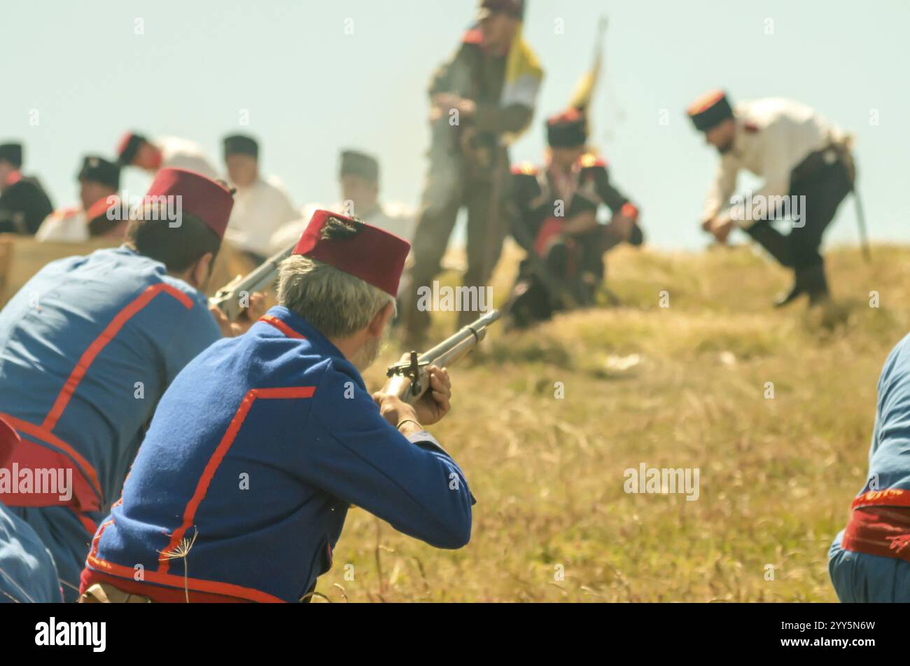 Truppe von Soldaten, die Gewehre während einer historischen Nachstellung auf einem Hügel, 16.12.2024, zielten Stockfoto