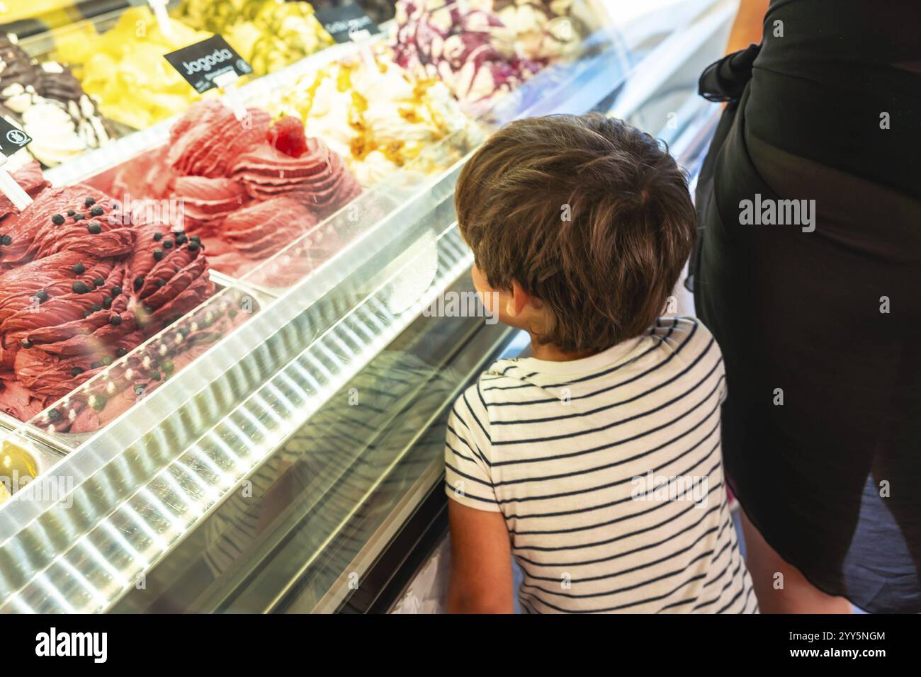 Kind, das bunte Eissorten in einem Geschäft mit Kühlschränken ansieht und den Sommerurlaub in piran, slowenien, genießt Stockfoto