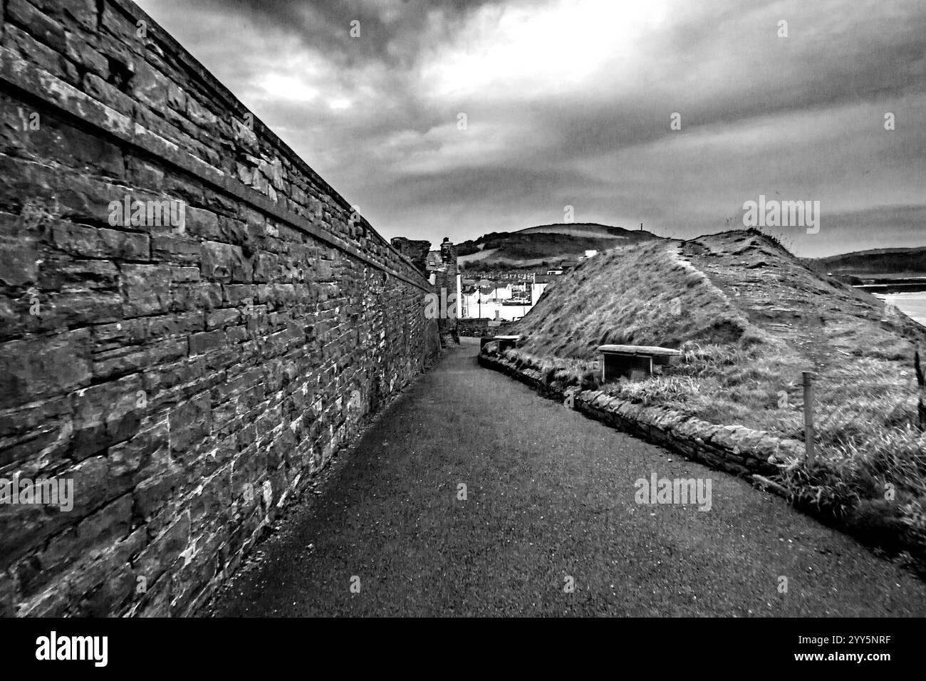 Pfad, der von der Landzunge hinunter führt, wo sich die Ruinen der Burg befinden, in Richtung der Stadt Aberystwyth in Schwarz-weiß Stockfoto