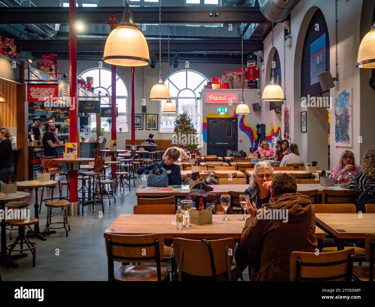 In der festlichen Produce Hall in Stockport, Großbritannien, genießen Besucher Speisen und Getränke in einer lebhaften Atmosphäre. Stockfoto