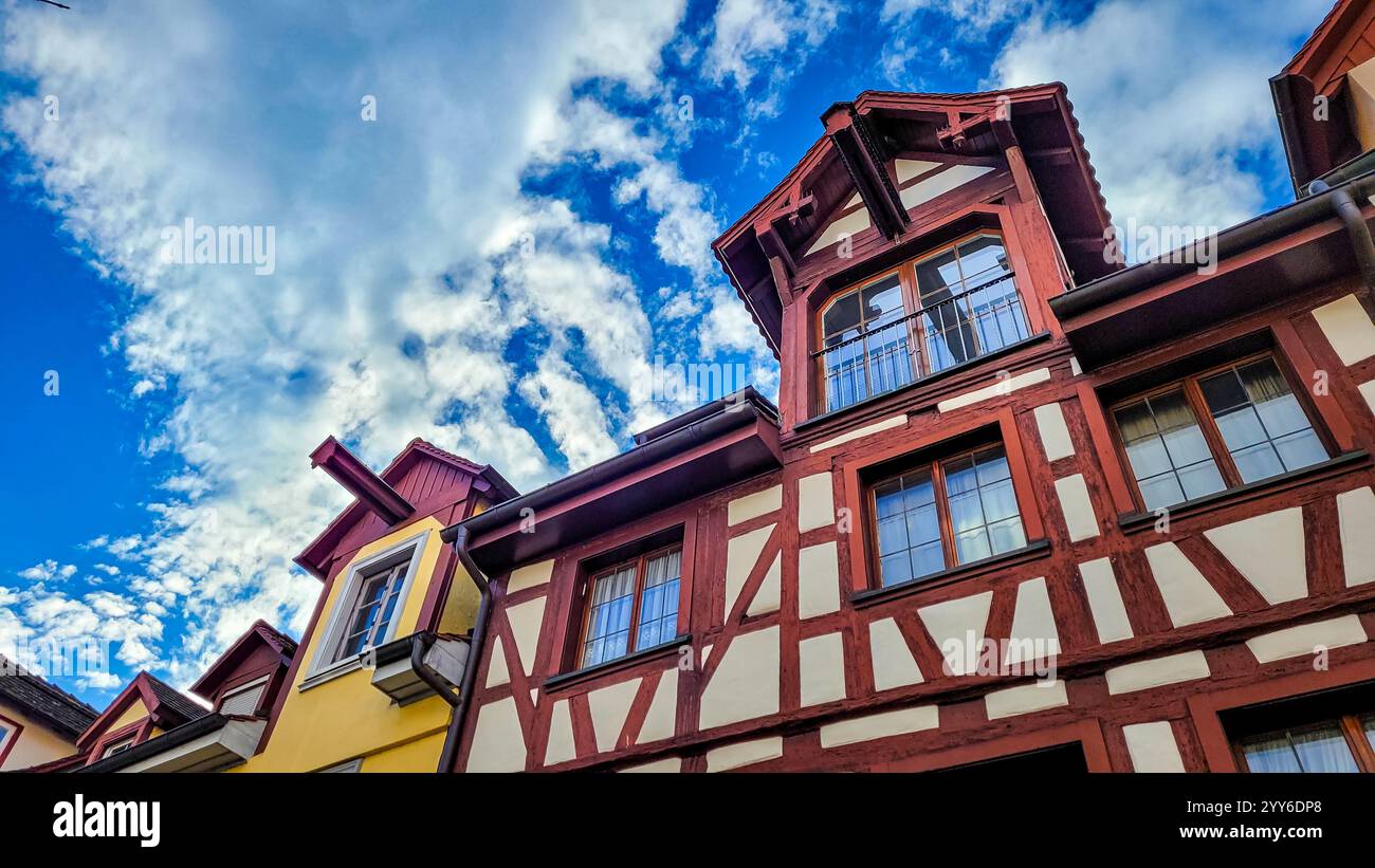 Schöne und charmante mittelalterliche Holzrahmenhäuser mit einem Lastkran auf dem Dach vor dem Hintergrund des blauen Himmels mit weißen Wolken Stockfoto