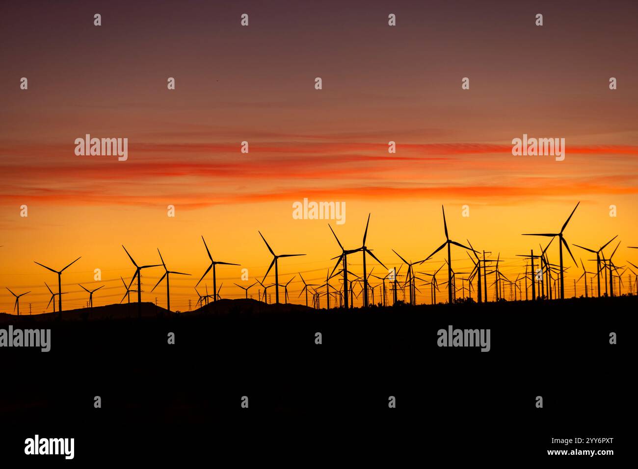 Windmühlen säumen den Horizont bei Sonnenuntergang in der Nähe von Mojave, Kalifornien, in der Wüste. Stockfoto