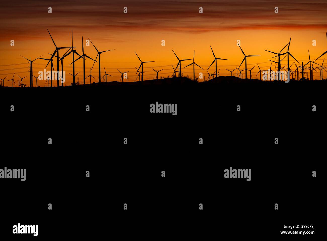 Windmühlen säumen den Horizont bei Sonnenuntergang in der Nähe von Mojave, Kalifornien, in der Wüste. Stockfoto